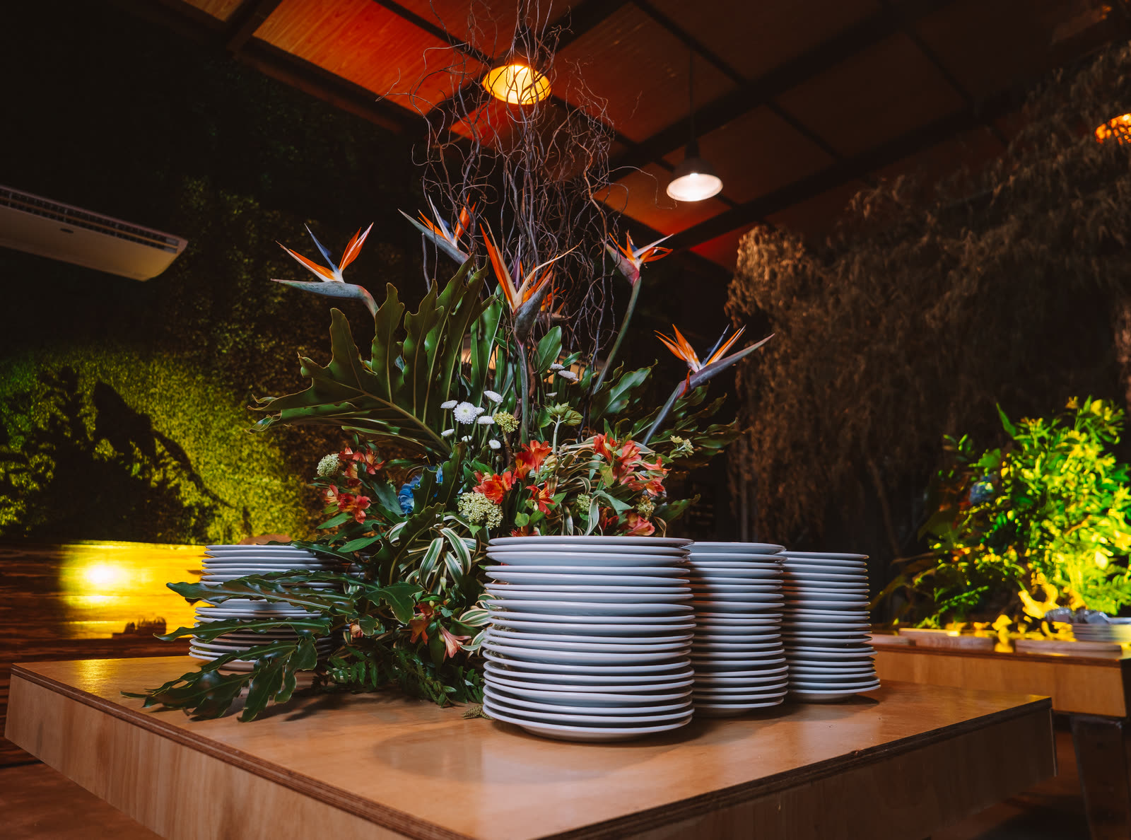 Ilha de bufê com pratos e arranjo de flores tropicais na Apogeo